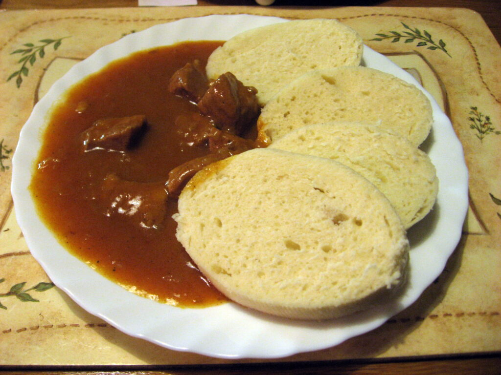 Czech goulash (guláš) with bread dumplings (knedlíky) in rich sauce – traditional dish in Prague Food Guide