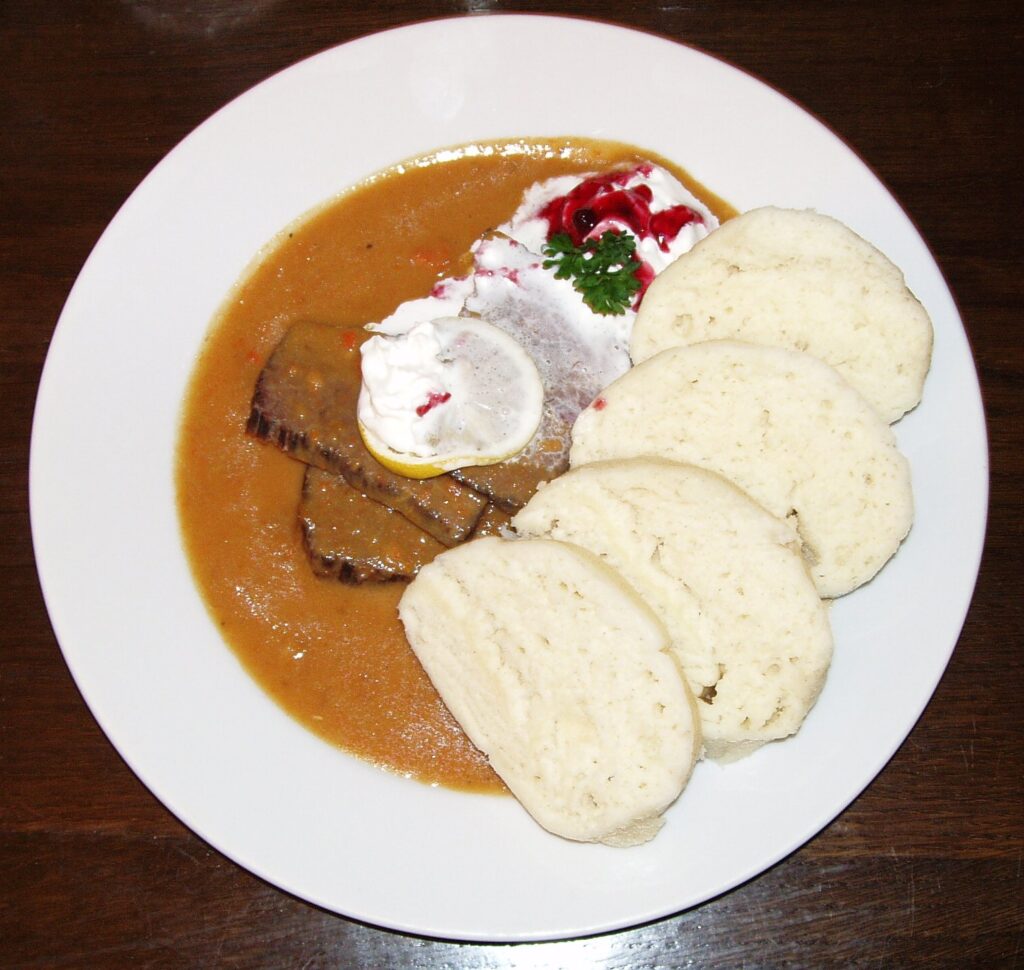Svíčková na smetaně with beef, creamy vegetable sauce, bread dumplings, and cranberry garnish – traditional Czech dish in Prague Food Guide