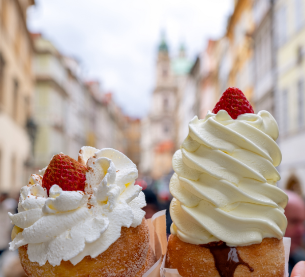 Traditional Czech trdelník dessert topped with whipped cream and strawberries in Old Town Prague – Prague Food Guide
