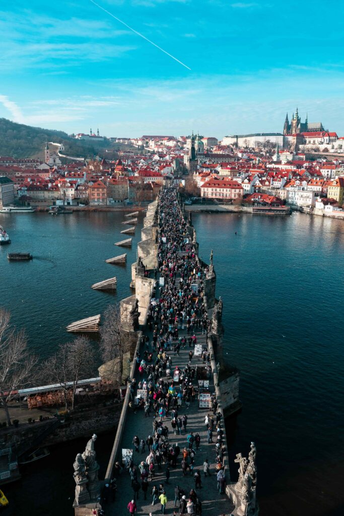 Busy Charles Bridge in Prague filled with tourists, highlighting why to visit at sunrise or late night instead of peak hours