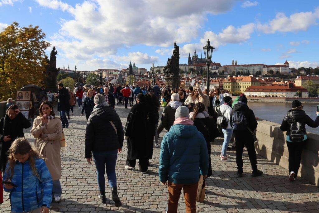 Crowded Charles Bridge in Prague during midday with heavy tourist traffic, showing the worst time to visit