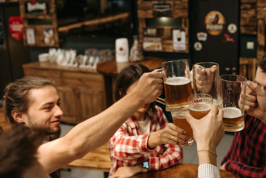Group of friends clinking beer glasses together in a Prague pub