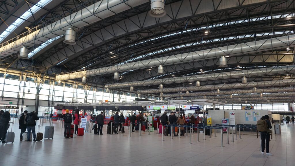 Travelers checking in at Prague Airport terminal with luggage and departure counters