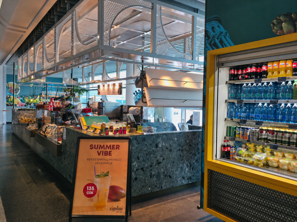 Airport cafe counter with drinks fridge and snack display inside a modern terminal