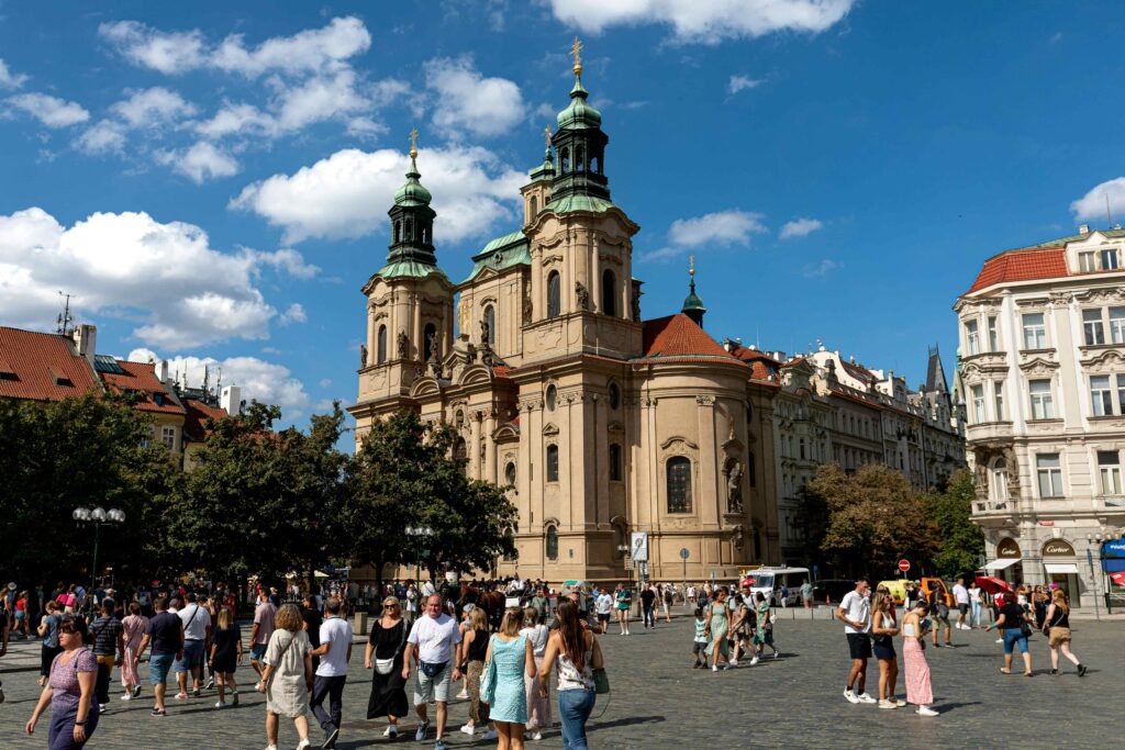 Crowd of tourists in a busy square near a historic church in Prague