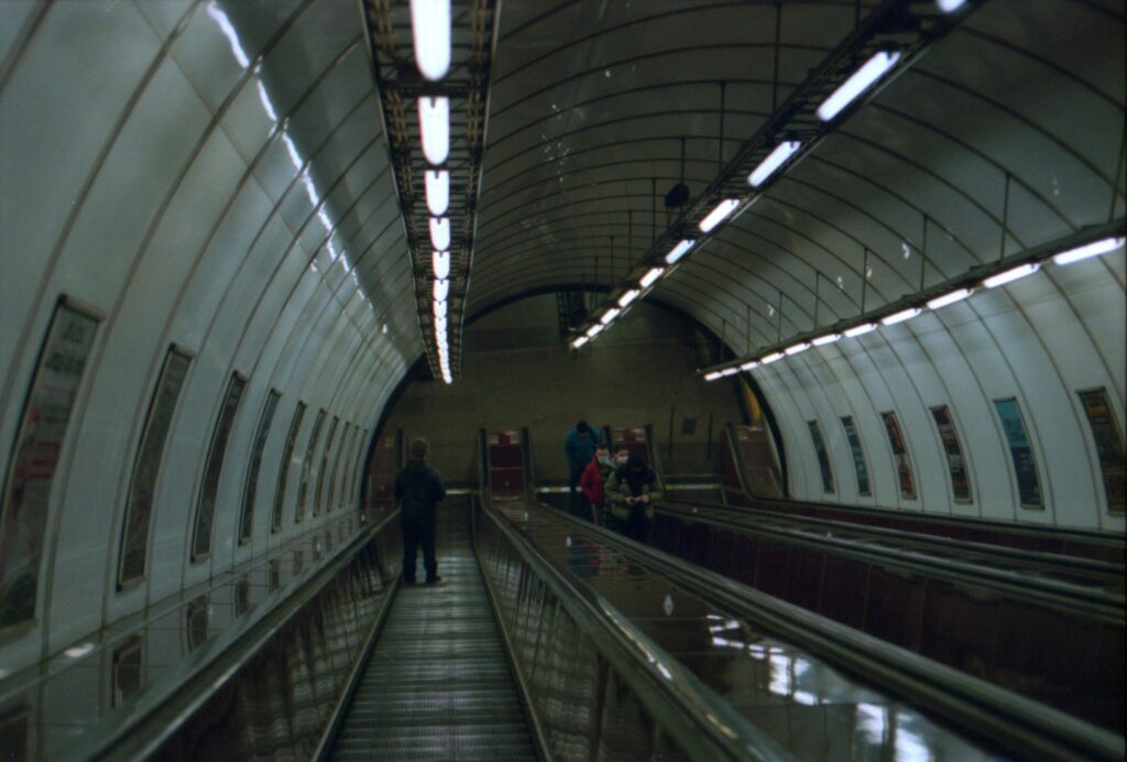 People standing and walking on an escalator inside a Prague metro station