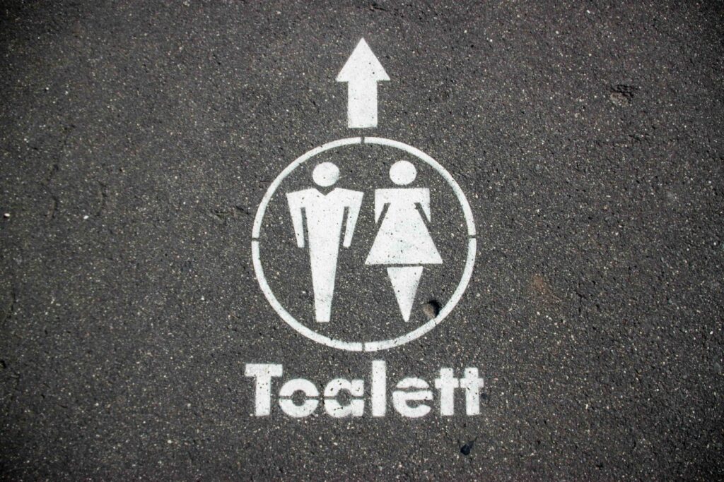 public toilet sign in Prague indicating paid access and the need for small coins