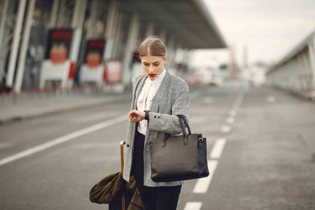 Traveler checking the time while walking with luggage in a city, showing a rushed travel moment