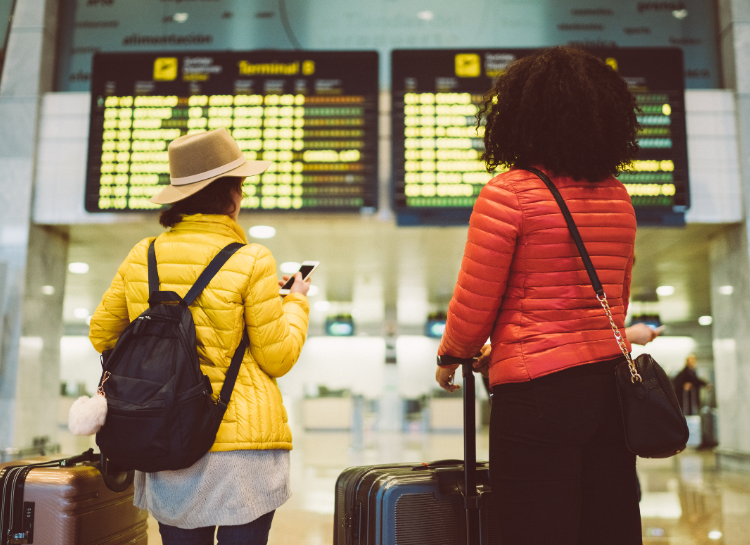 Travelers checking flight information with luggage at Václav Havel Airport Prague arrivals hall