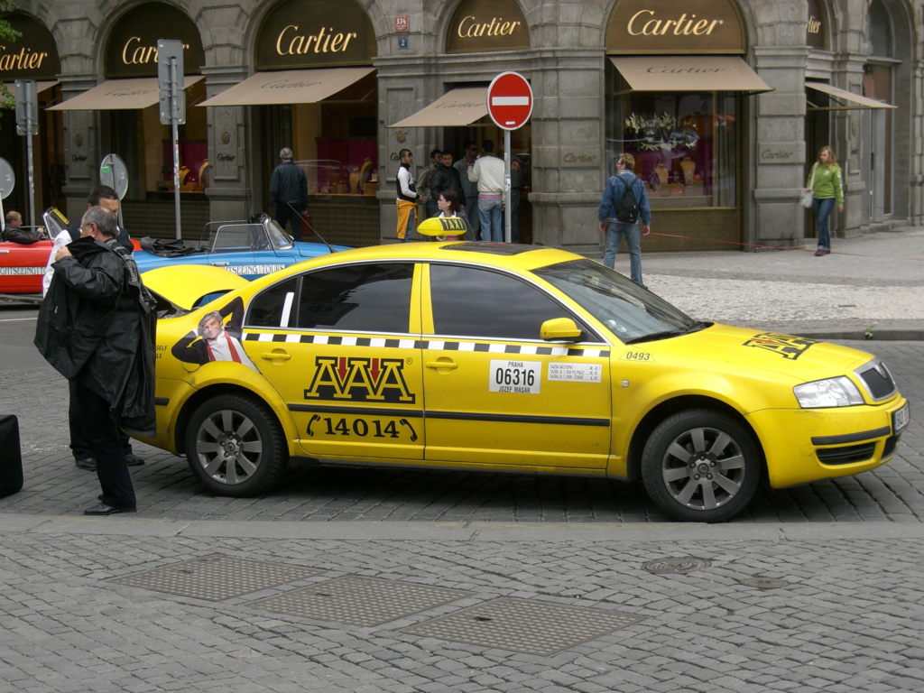 Traditional yellow Prague Taxis parked in Prague city center, illustrating Prague taxi safety, tourist scams, Uber and Bolt transportation in Prague in 2026.