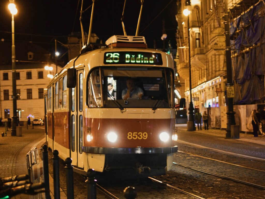 Night tram traveling through historic city street with illuminated route display and street lights