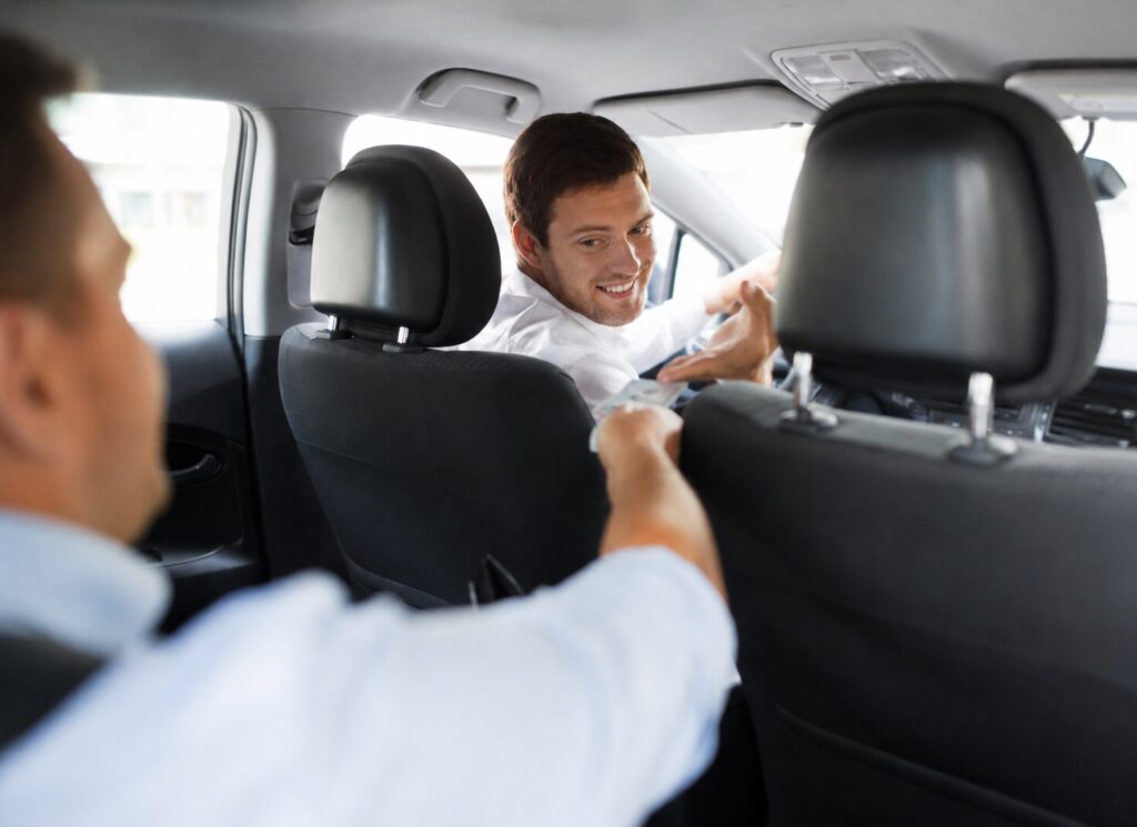 Tourist paying for a Prague taxi ride inside a car, illustrating real Prague taxi prices in 2026, airport rides, surge pricing and taxi payment in Prague.