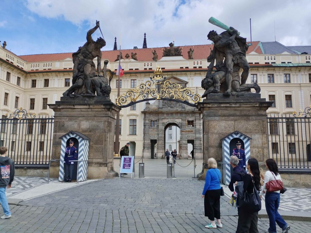 Main entrance gate of Prague Castle with castle guards and giant fighting statues at Hradčanské Square in Prague, Czech Republic, photographed near the popular Tram 22 entrance route.