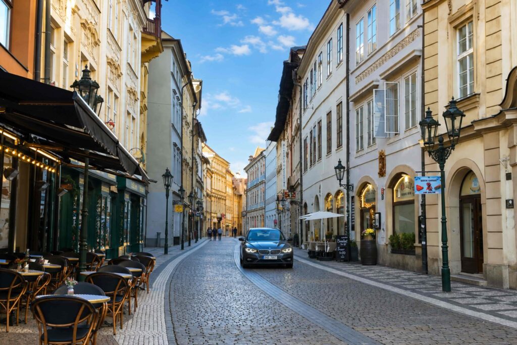 Celetná Street, one of the most famous Prague Streets, with historic architecture, cobblestone pavement, cafés, and a sunny blue sky