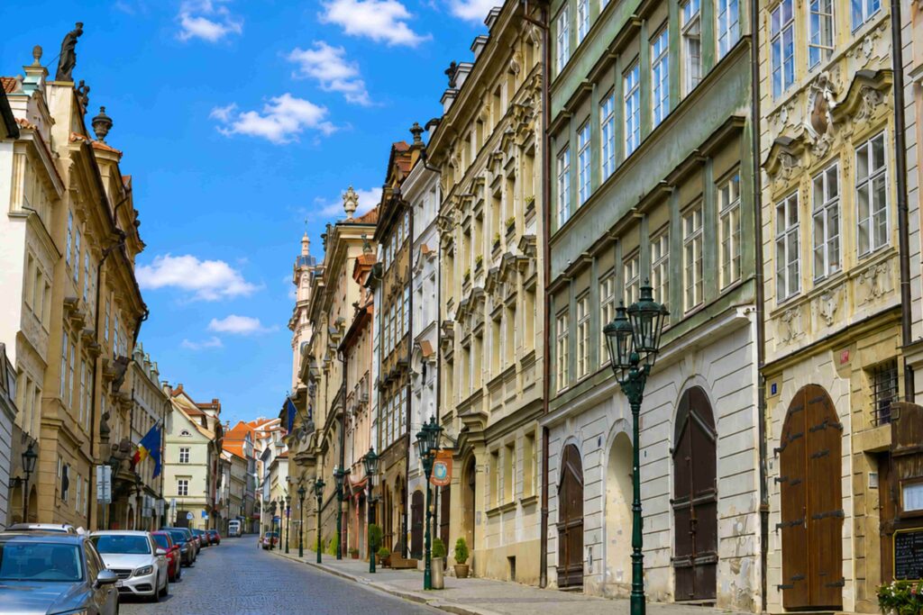 Nerudova Street, one of the most beautiful Prague Streets, featuring historic Baroque buildings, cobblestone pavement, and a sunny blue sky