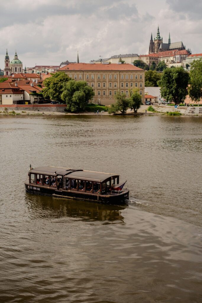 Prague Rivers with a boat on the Vltava River and Prague Castle in the background