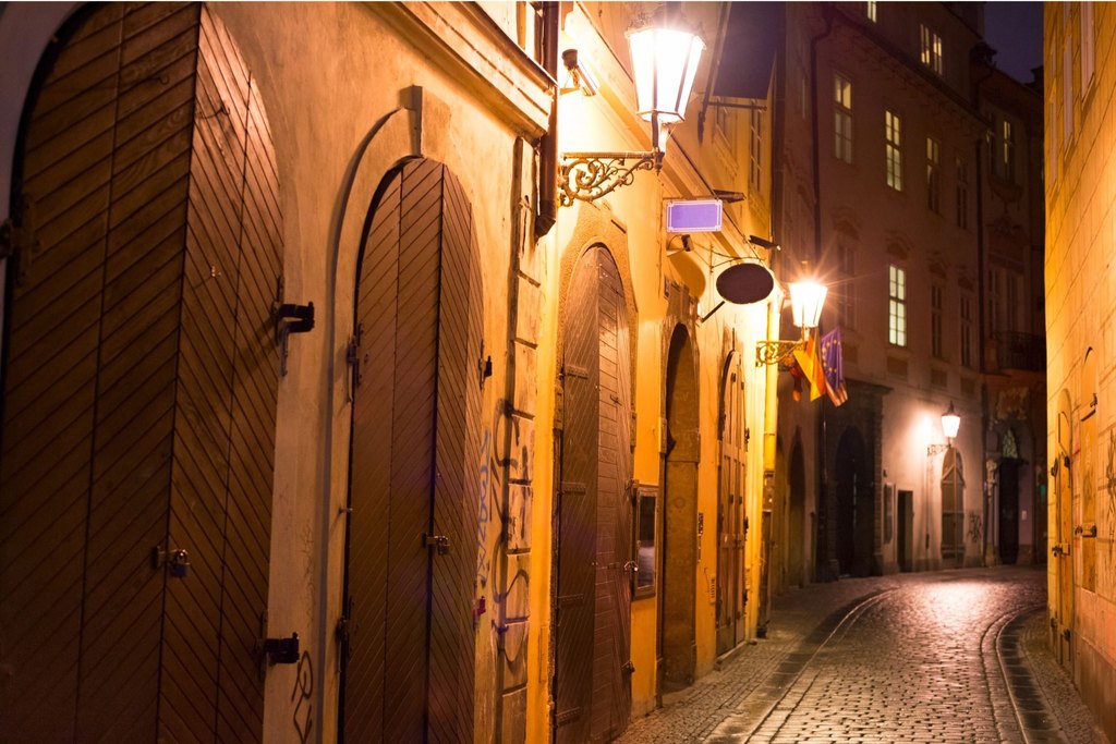 rague Night Activities featuring a historic Prague street illuminated by warm lanterns at night, perfect for a ghost and dark-history tour